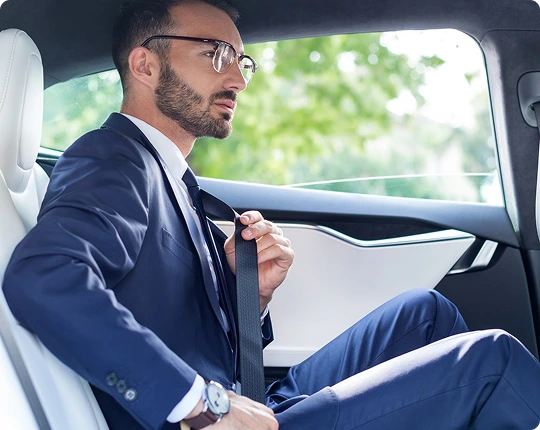 Business traveler in a suit fastening his seatbelt in the backseat of a luxury car, emphasizing safety and professionalism.