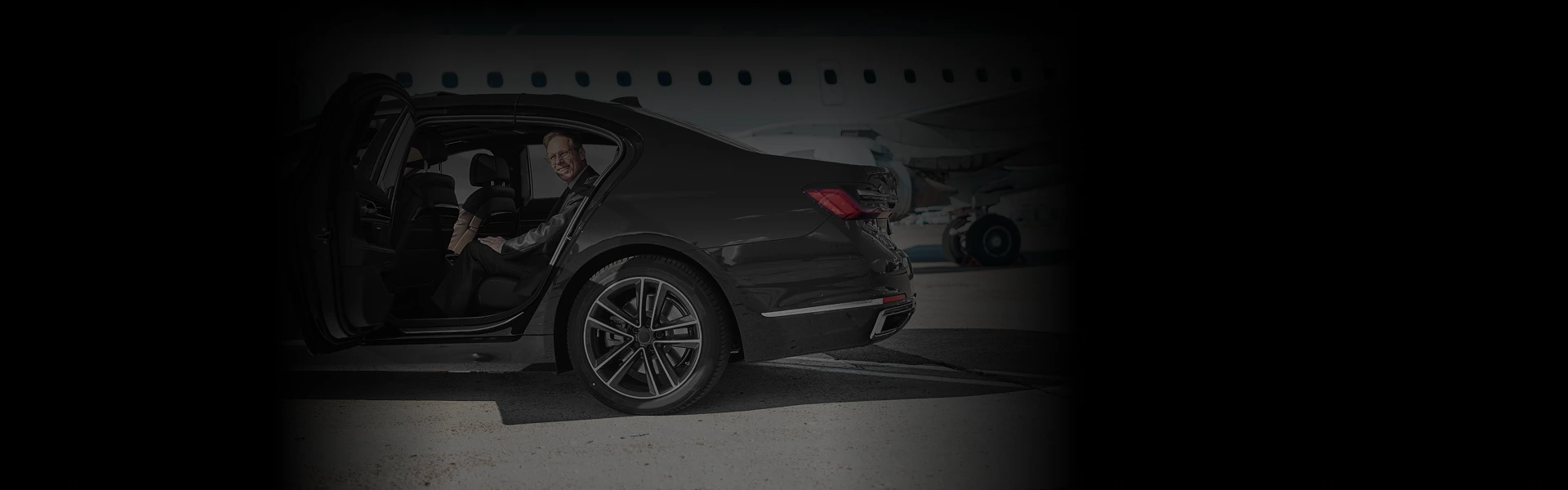 Business traveler boarding a black luxury sedan at O'Hare Airport