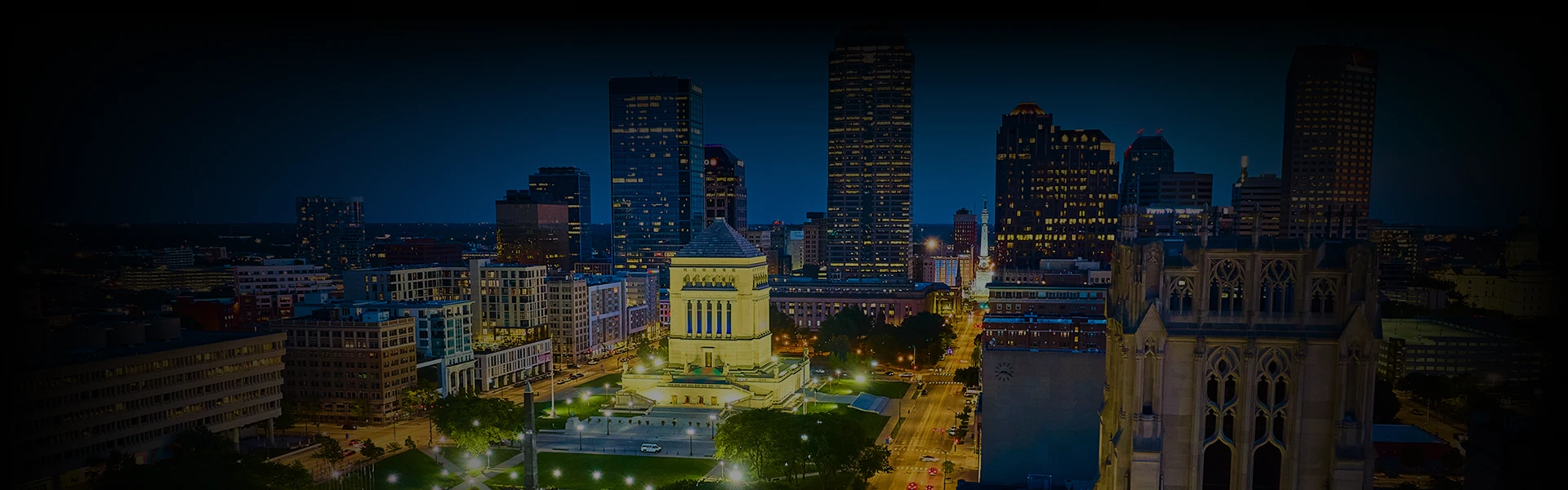 Night view of downtown Indianapolis with booking form for Prestige Ride's chauffeur service from Chicago to Indianapolis