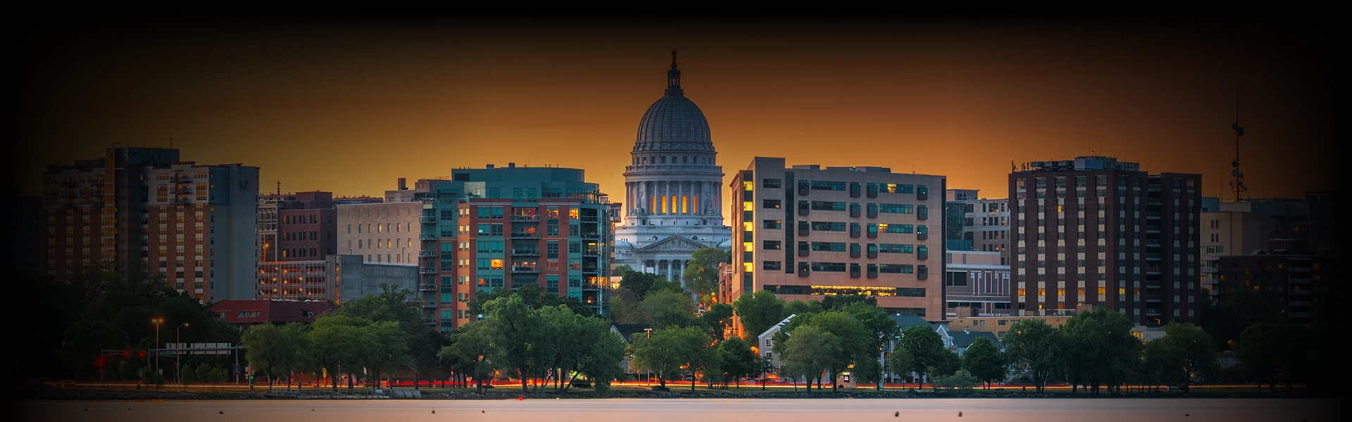 Evening view of the Madison, Wisconsin skyline with the State Capitol building, overlaid with a chauffeur service booking form