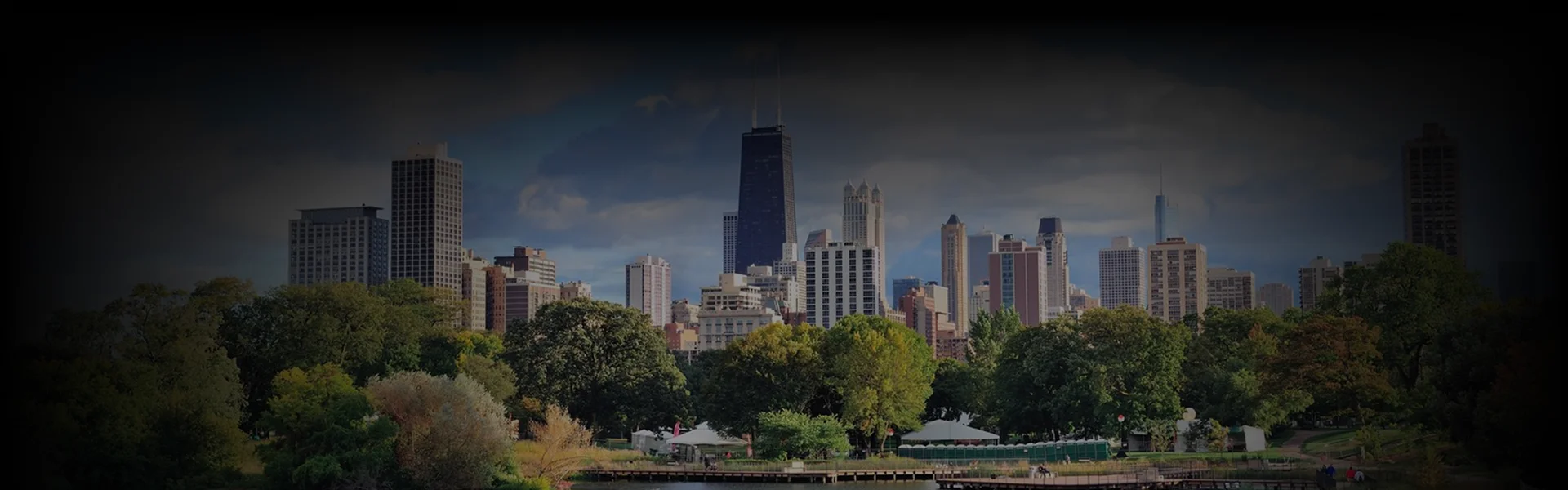 Skyline view of downtown Illinois framed by green trees under a clear sky, showcasing premium Car Service Illinois with black car and limo rides.